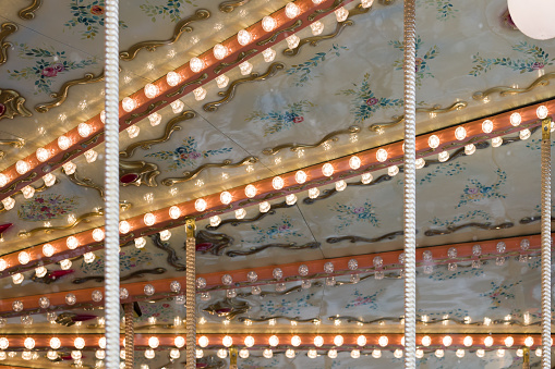 Closeup of lights of French carousel in a holiday park. traditional old fairground vintage carousel. Merry-go-round with horses.