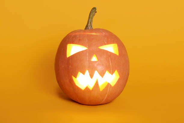 istock Composition of glowing light from inside jack o lantern, pumpkin isoalted over yellow background, celebrating holiday, last October night, orange pumpkin against studio wall. Halloween concept. 1180750512