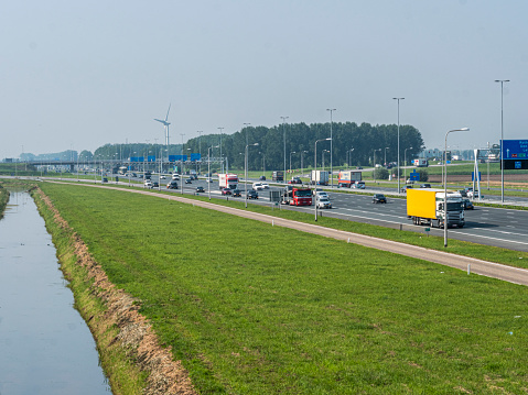 High angle view of the A4 motorway between Amsterdam and The Hague in the Netherlands. Wind turbines and traffic visible in a flat landscape.