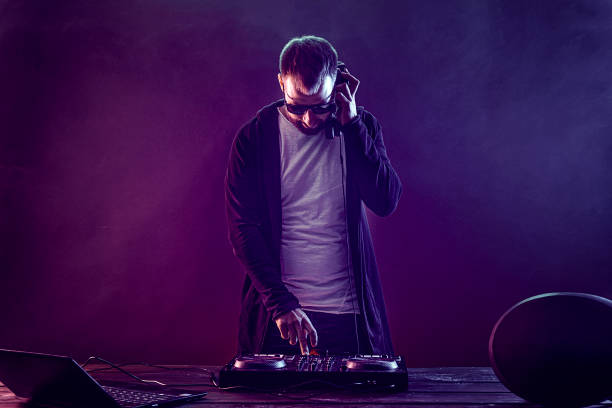 istock Trendy male dj posing against mixing console 1180754630