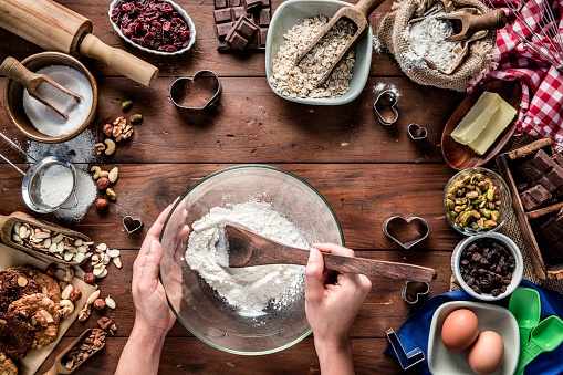 Woman hands making chocolate and nuts cookies on rustic table with digital food weight scale.  Christmas themes.