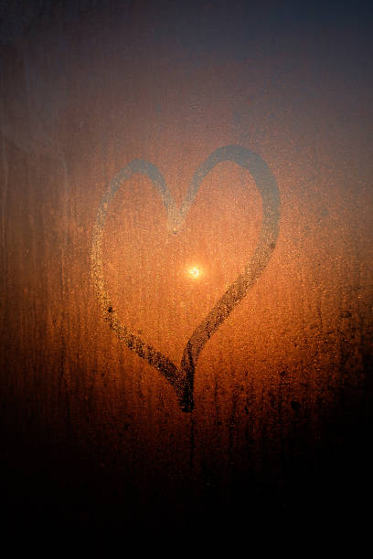 istock Drawed heart on condensated window with sunrise on background 1180759192