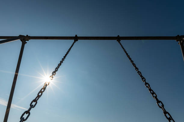 Sun shines through a metal chain swing