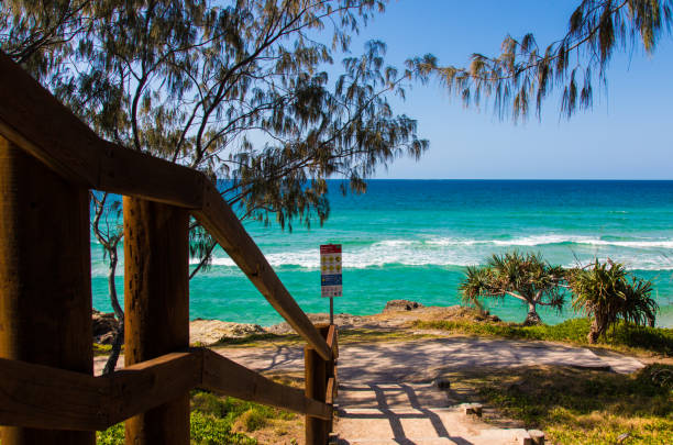 Rocky and sandy bay at Coolum, Queensland, Australia. Midground featuring Point Arkwright. White breaking surf with some swimmers. Beautiful sunny day with clear blue sky. Ocean is deep blue and turquoise colour.