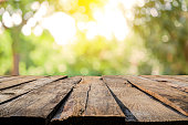 Backgrounds: Empty wooden table with defocused yellowish lush foliage at background