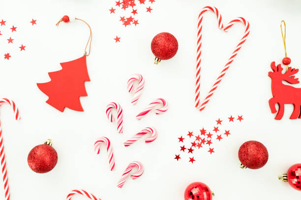 istock Christmas or New Year composition. Red toys, candy canes and confetti on white background. Flat lay, top view. 1180762237