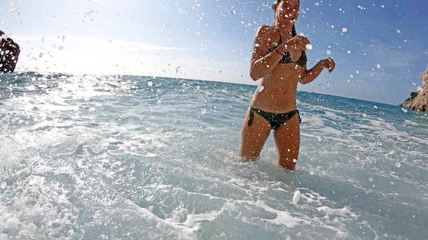 Carefree woman having fun while running through sea in summer day. Copy space.