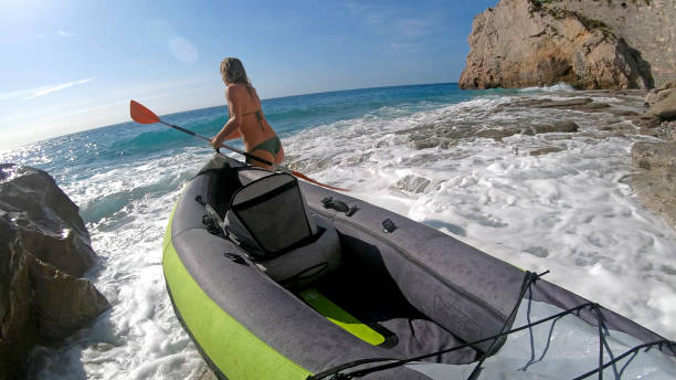istock Young woman launches kayak from beach 1180765692