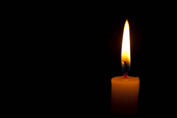 istock Horizontal photo of lighted candle isolated on black background 1180772284