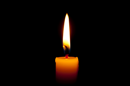 Burning candle isolated on black background. Copy space. Close up.