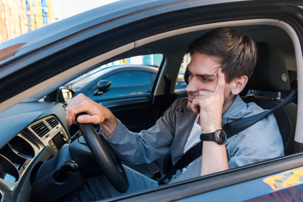 Annoyed buisnessman in car late for meeting Annoyed tired young man is riding driving car. Businessman is late for meeting. Driver brunette in grey suit stuck in traffic jam. Stressful situations on roads and fast rhythm in modern city. impatient stock pictures, royalty-free photos & images