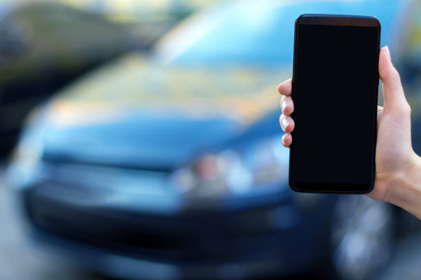 istock Hand with smartphone on background with car 1180774630