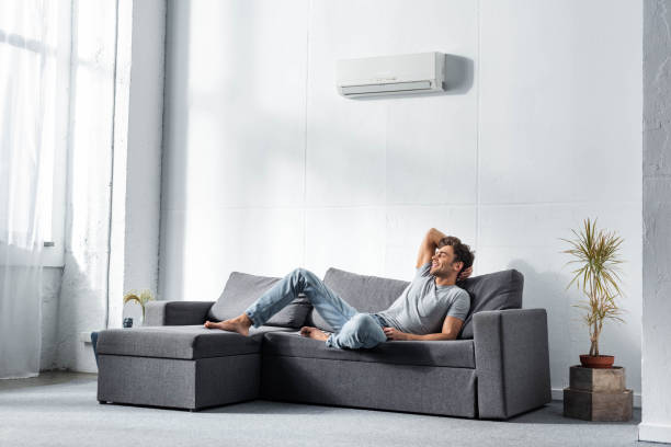 handsome and smiling man in jeans and t-shirt lying on sofa