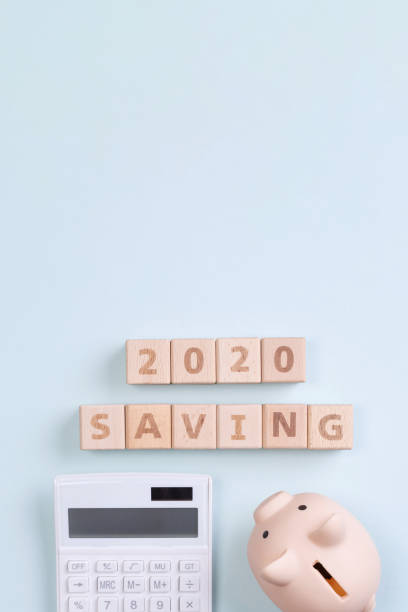 istock 2020 goal, finance plan abstract design concept, wood blocks on blue table background with piggy bank and calculator. 1180777195