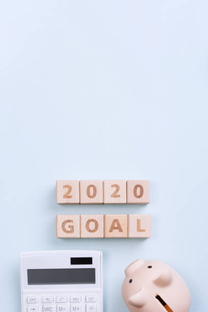 istock 2020 goal, finance plan abstract design concept, wood blocks on blue table background with piggy bank and calculator. 1180777228