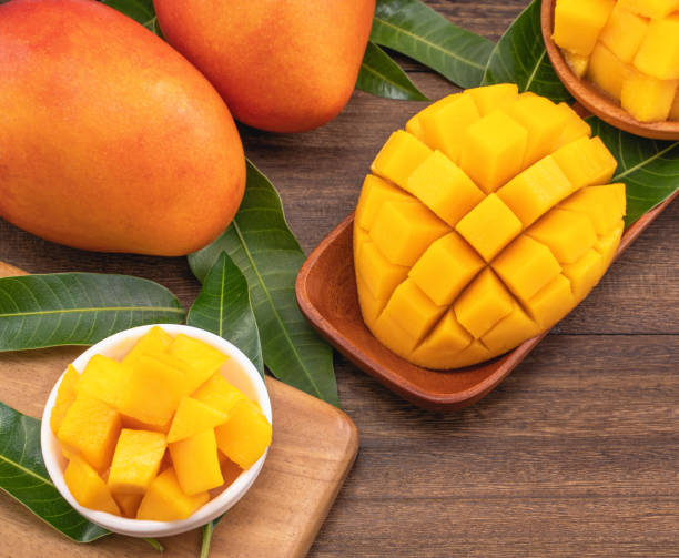 istock Fresh mango, beautiful chopped fruit with green leaves on dark wooden table background. Tropical fruit design concept. 1180777401