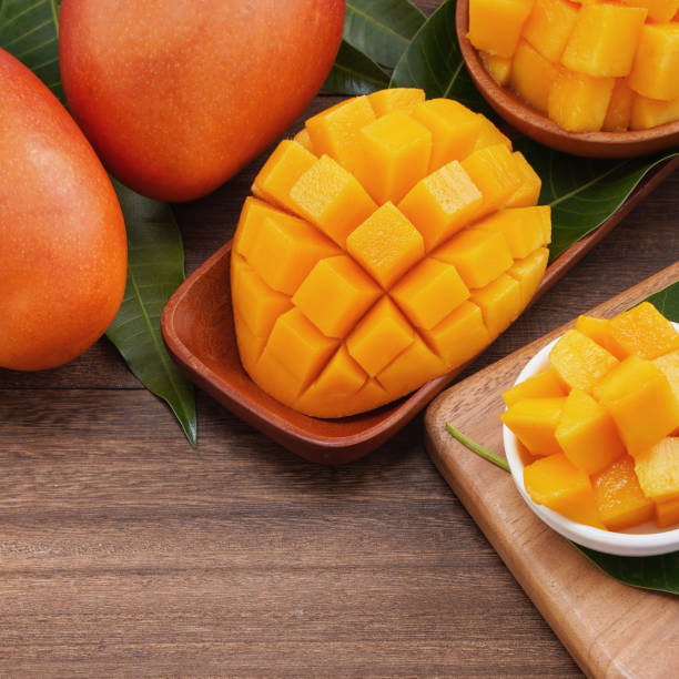 istock Fresh mango, beautiful chopped fruit with green leaves on dark wooden table background. Tropical fruit design concept. 1180777408