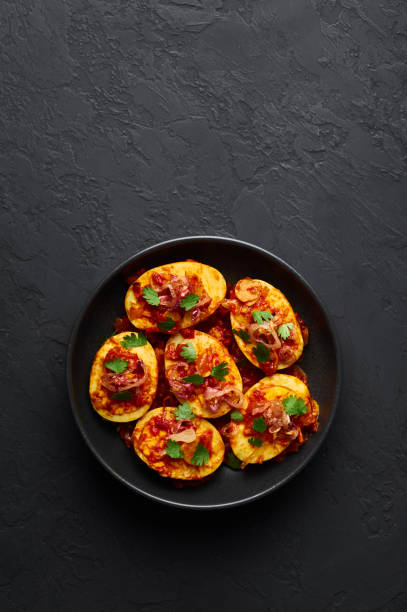 istock Golden Egg Curry in black bowl at dark slate background. Burmese Egg Curry is popular Myanmar Cuisine dish with duck or chicken eggs, tomatoes, ginger, onion, cilantro and spices. 1180777791