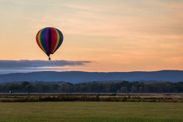 istock Rainbow hot-air balloon floats over field at sunrise 1180778408