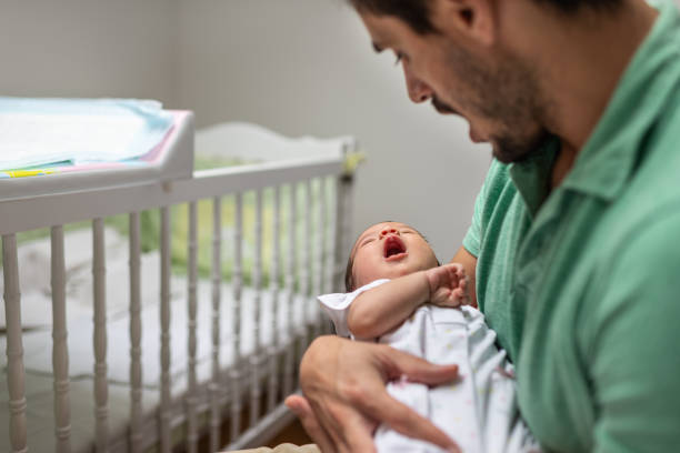 istock Newborn baby yawning in father's hands 1180778444