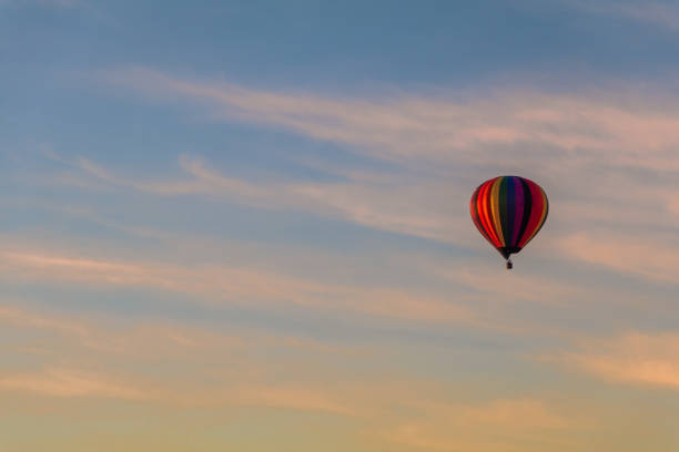 istock Rainbow hot-air balloon isolated in colorful clouds at sunrise 1180779634