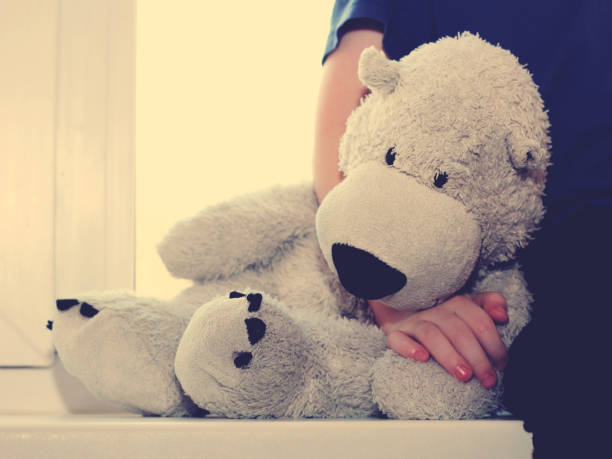 istock bear sad toy sitting on the window so close, toned 1180780773