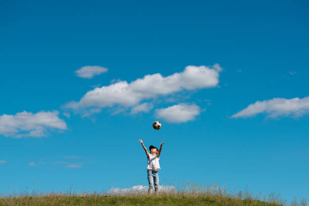 Child playing with soccer ball in meadow