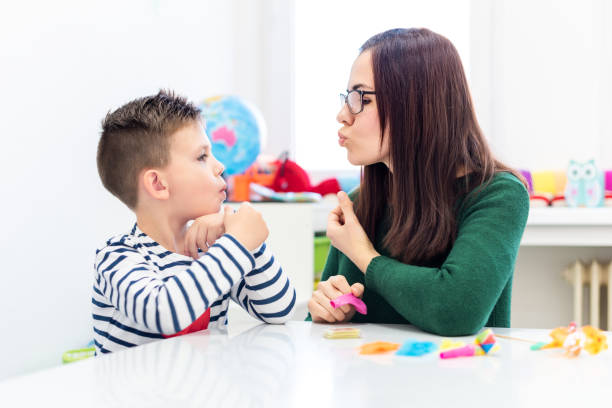 istock Children speech therapy concept. Preschooler practicing correct pronunciation with a female speech therapist. 1180784517
