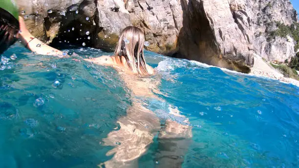 Photo of Young woman explores the sea caves while holding onto kayak