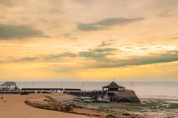 istock beach image with harbour and moored boats with a sandy beach at sunrise 1180792376