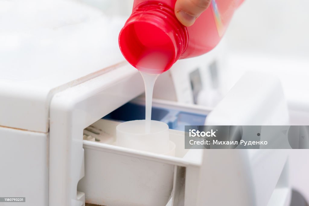 pouring the washing conditioner in the washing machine to get clean clothes Washing Machine Stock Photo