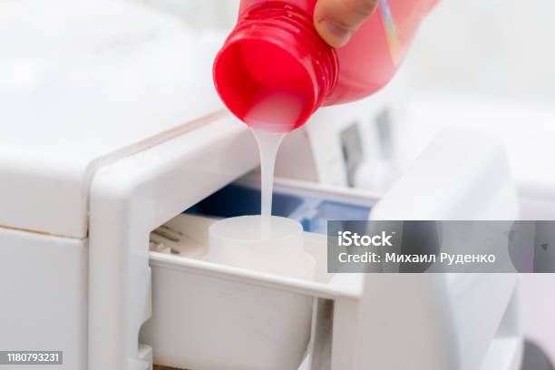 Pouring The Washing Conditioner In The Washing Machine To Get Clean Clothes Stock Photo - Download Image Now