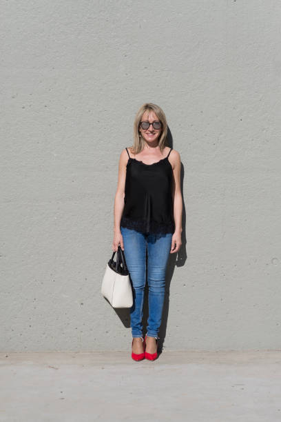 istock Blonde woman leaning on a white wall while looking camera 1180795087