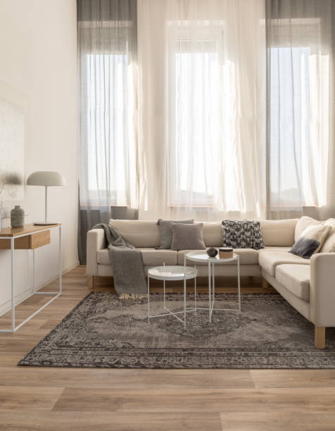 istock Beige comfortable corner sofa with grey pillows in elegant living room interior with white wall 1180795147