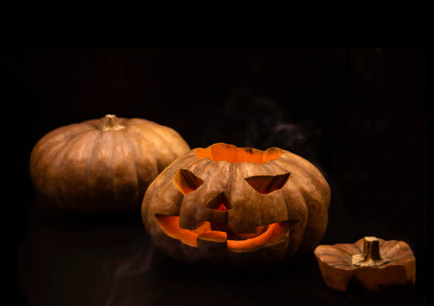 istock Pumpkin that is cut into a ghost face for Halloween, placed in a scary atmosphere, with candles shining in the dark. For use on Halloween 1180795720
