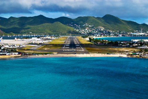 Point Salines, St. George's, Grenada: Maurice Bishop International Airport (GND / TGPY), formerly known as Point Salines Airport - aerial view of the main terminal, air side and apron. The airport was built around 1980 to replace the older Pearls airfield in the northeast of the island. It was designed by Canadian engineers and built primarily by European companies, although the labor force used was primarily Cuban.