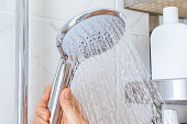 Woman hand using shower head in bathroom.