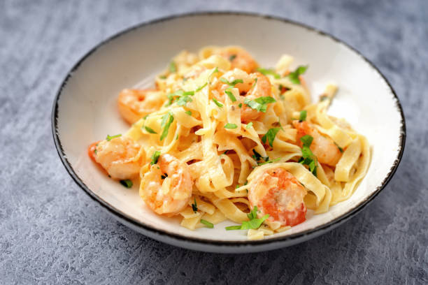 Close up of shrimp fettuccine alfredo on blue background Close up of shrimp fettuccine alfredo on blue background food state preparation shrimp prepared shrimp stock pictures, royalty-free photos & images