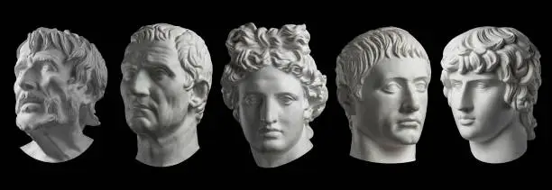 Five gypsum copy of ancient statue of Seneca, Guy Julius Caesar, Apollo, Germanicus and Antinous heads for artists isolated on a black background. Plaster sculpture of mans faces.