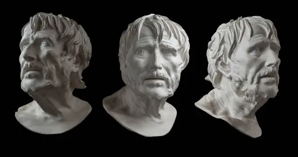 Photo of Three gypsum copy of ancient statue head of Lucius Seneca isolated on black background. Plaster sculpture aged man face.