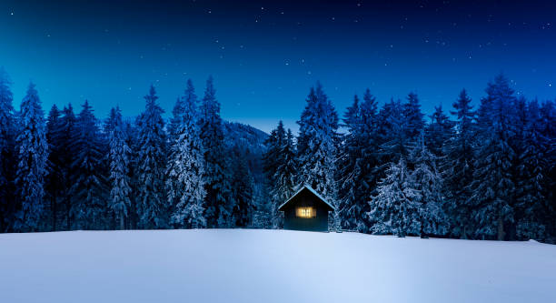 blockhütte mit glänzendem fenster im winterlichen wald - winter forest woods wintry landscape stock-fotos und bilder