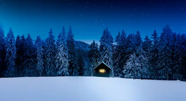 Photo of Log cabin with shining window in wintry forest