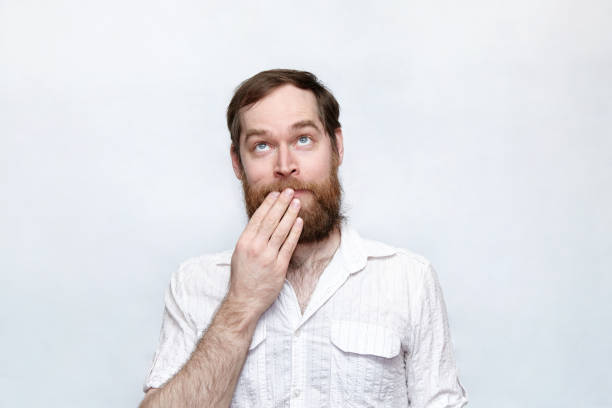 istock Shy man covering his mouth and looking up 1180802383
