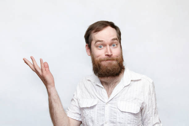 Confused man with hand raised over gray background Portrait of a bearded man with a scar on the cheek pointing the right direction confusion raised eyebrows human face men stock pictures, royalty-free photos & images