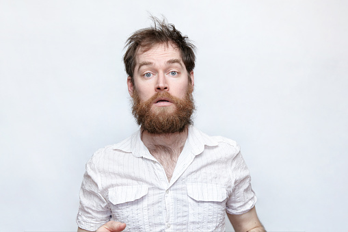 Hombre barbudo con corte de pelo desordenado sobre fondo gris photo