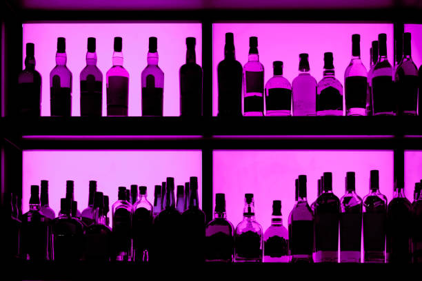 Bottles sitting on shelf in a bar Bottles sitting on shelf in a bar, back lit with neon blue Gin stock pictures, royalty-free photos & images