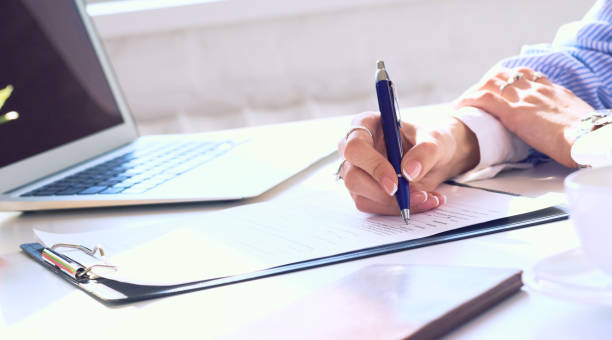 istock Businesswoman sitting at office desk signing a contract or making notes. 1180805208