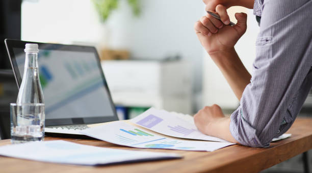 Side view of experienced businessman looking at financial data with graphics and charts while work on a laptop computer.