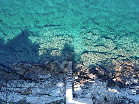 Beautiful beach of stones with stairs at fisherman town, Dalmatia, Croatia. Island Solta with crystal clean  water, south of Split, famous landmark and travel touristic destination in Europe.