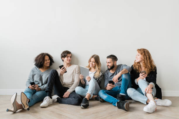 istock Happy young intercultural friends with gadgets watching funny video 1180810973
